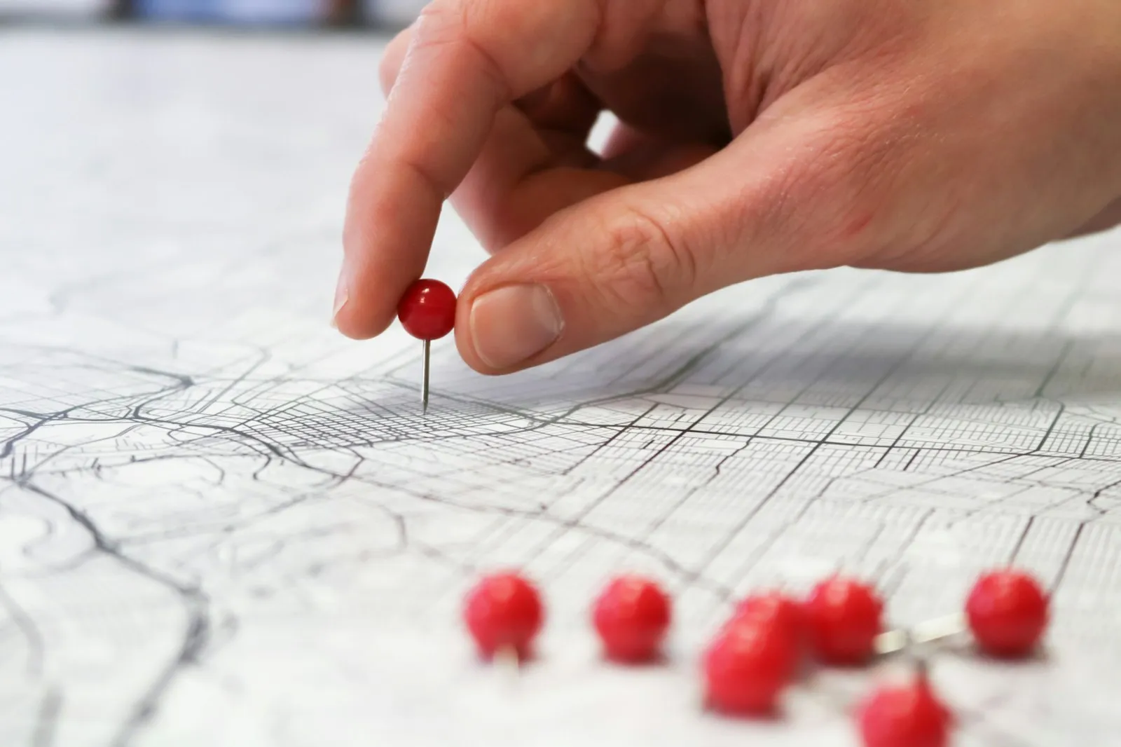 Hand placing a red pin on a city map